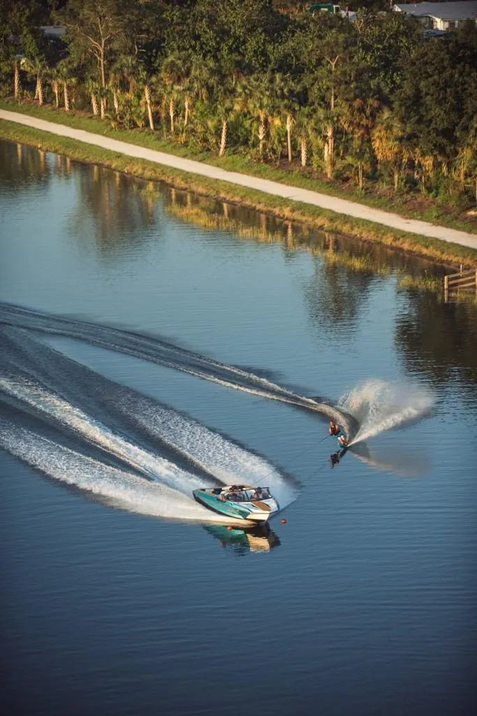 Slide: The Image of 2023 Nautique Ski boat towing a water skier on a calm lake. - 38