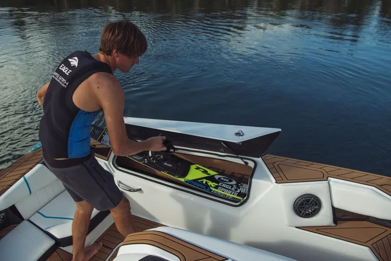 Slide: The Image of Man storing water ski in 2023 Nautique Ski boat compartment. - 42