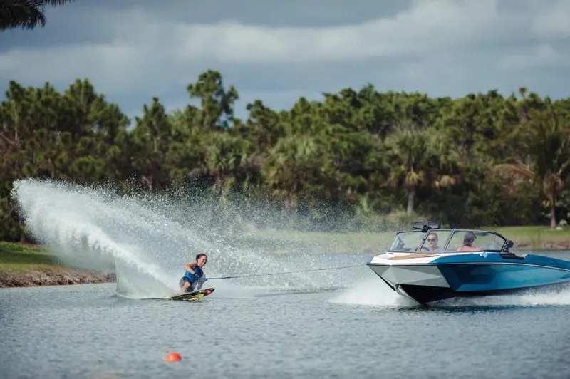 Slide: The Image of 2023 Nautique Ski boat towing a water skier on a lake. - 5