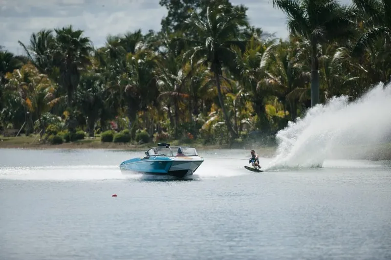 Slide: The Image of 2023 Nautique Ski boat towing a water skier on a tropical lake. - 7