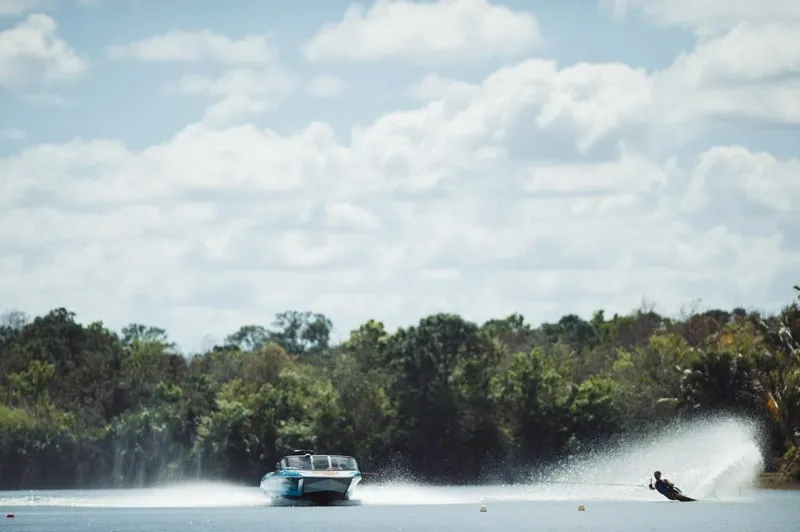 Slide: The Image of 2023 Nautique Ski boat towing a water skier on a sunny lake. - 8