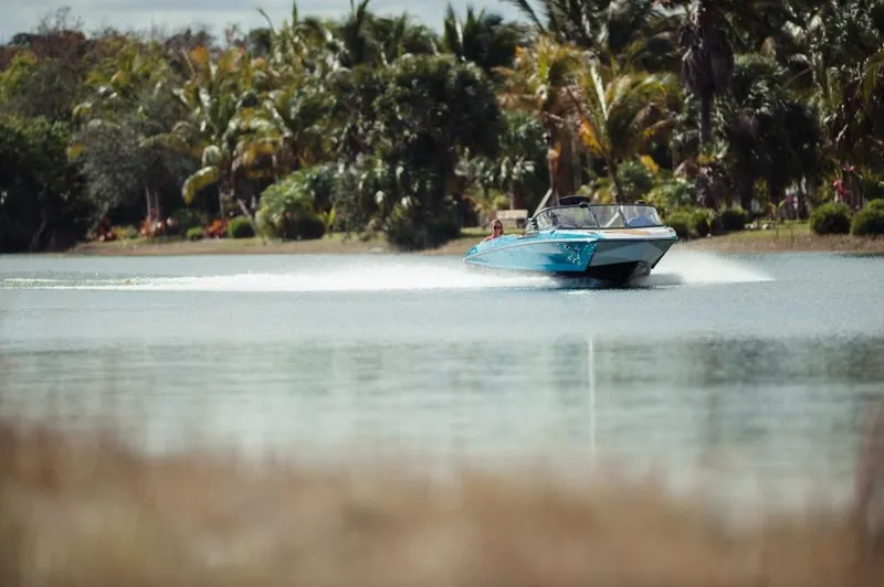 Slide: The Image of 2023 Nautique Ski boat cruising on a tropical lake. - 9