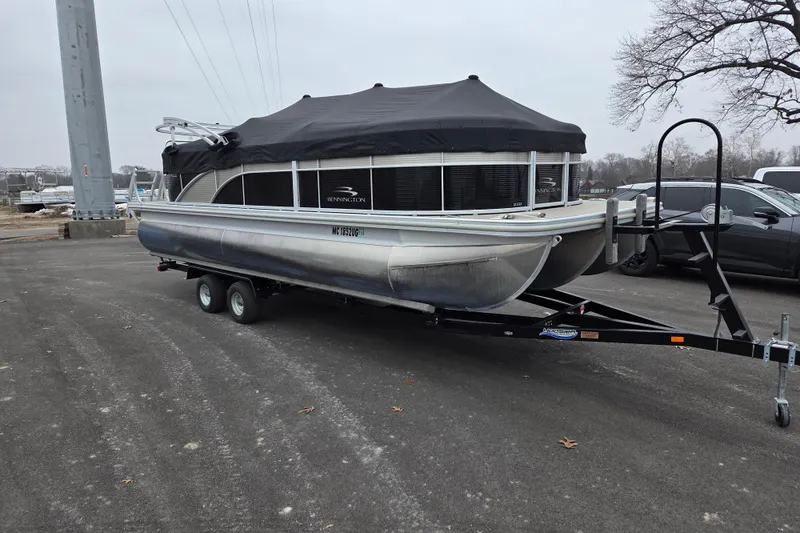 The Image of 2018 Bennington 22SSRX pontoon boat on trailer with black cover in parking lot. - 0