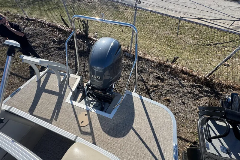 Slide: The Image of 2018 Bennington 22SSRX pontoon boat with Yamaha 150 outboard motor, parked near a fence. - 18