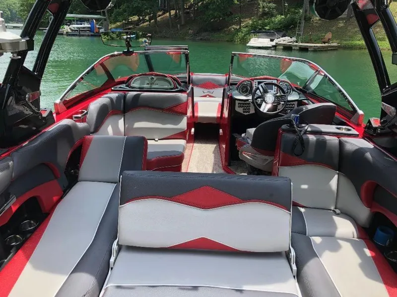 Slide: The Image of 2015 Supra SE 450 boat interior with red and gray seating on a lake. - 26