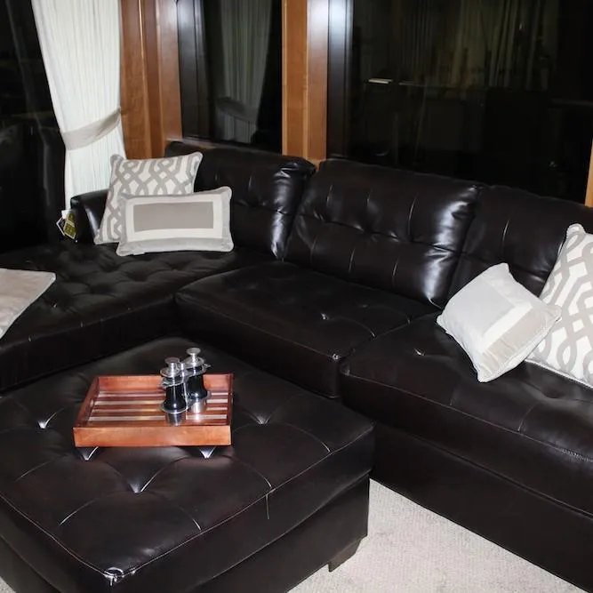 Slide: The Image of Luxurious black leather sectional sofa with decorative pillows and wooden tray in a modern living room. - 9