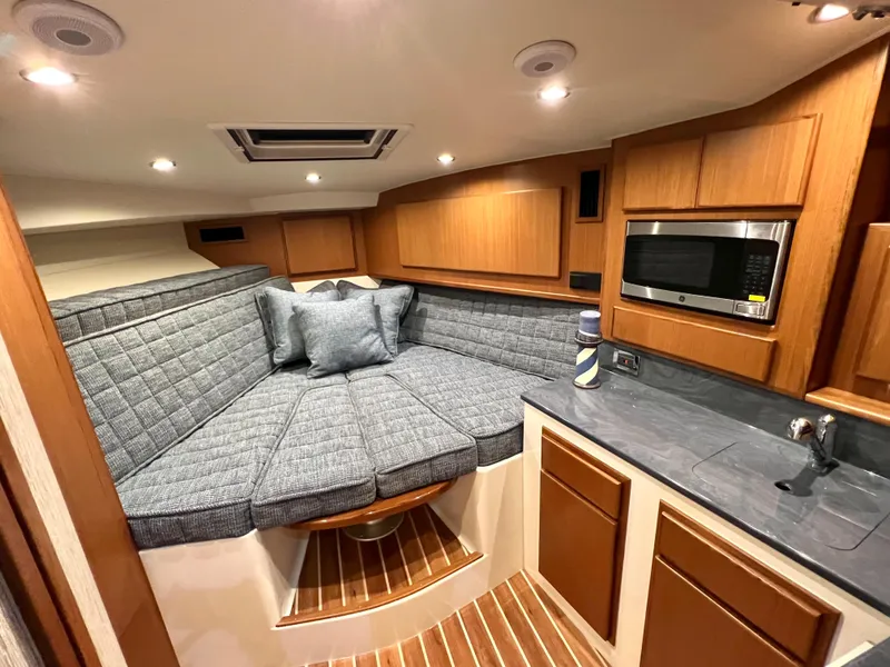 Slide: The Image of 2025 Henriques 30' Express cabin interior with cozy seating, modern kitchenette, and wood accents. - 18