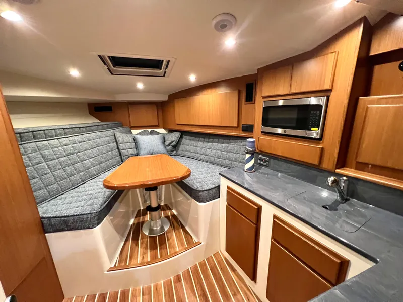 Slide: The Image of 2025 Henriques 30' Express cabin interior with seating, table, and kitchenette. - 19