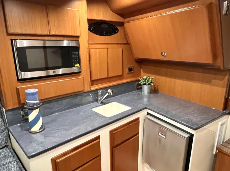 Slide: The Image of 2025 Henriques 30' Express boat kitchen with microwave, sink, and compact fridge. - 21