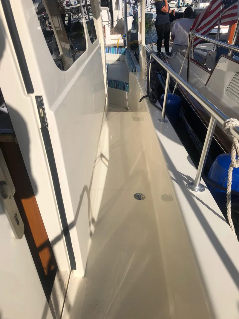 Slide: The Image of Henriques 42 Cruiser 2025 model, side deck view with railing and docked boats. - 13