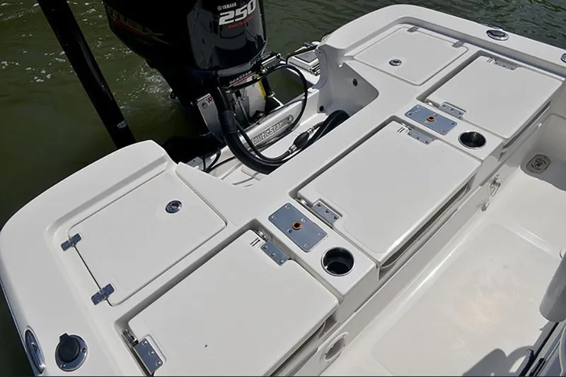 Slide: The Image of 2023 NauticStar 227 XTS boat stern with storage compartments and outboard motor. - 10