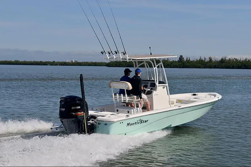 Slide: The Image of 2023 NauticStar 227 XTS boat cruising on a calm lake. - 2