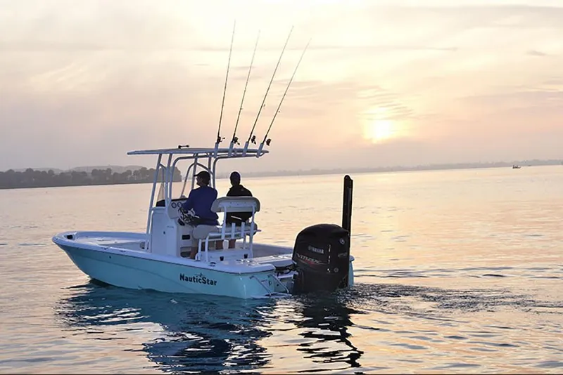 Slide: The Image of 2023 NauticStar 227 XTS boat on calm water at sunset. - 4