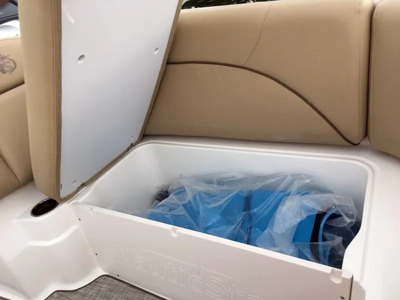 Slide: The Image of 2023 NauticStar 223DC Sport Deck storage compartment with beige seating. - 13