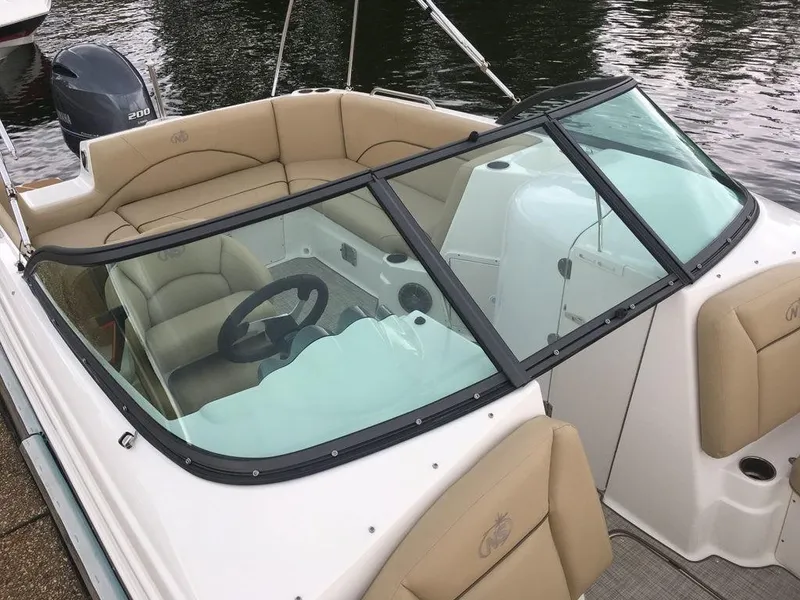 Slide: The Image of 2023 NauticStar 223DC Sport Deck boat interior with beige seating and black steering wheel. - 14