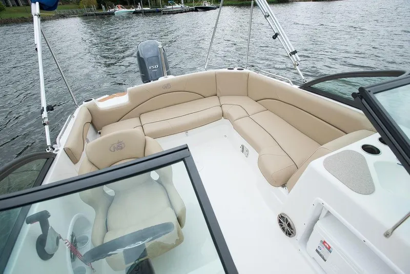 Slide: The Image of 2023 NauticStar 203DC Sport Deck boat interior with beige seating on the water. - 17