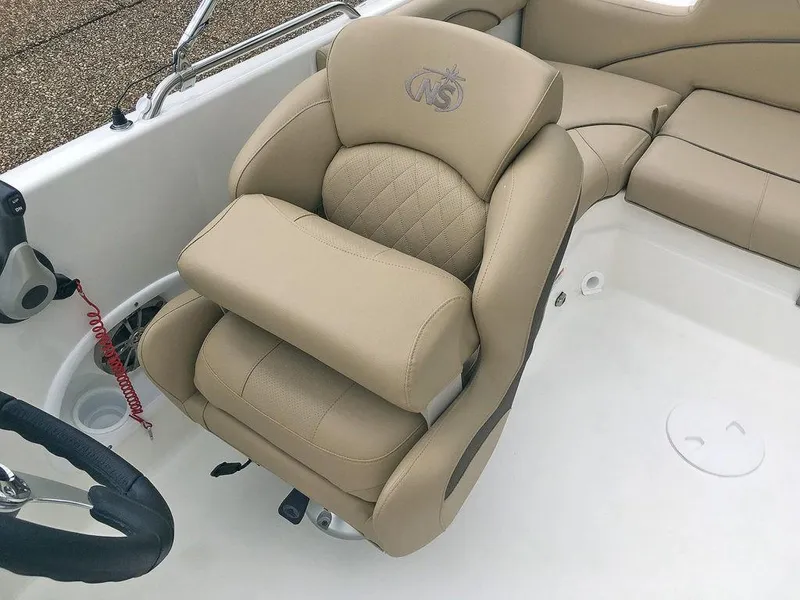 Slide: The Image of 2023 NauticStar 203SC Sport Deck boat with beige captain's chair and steering wheel. - 19