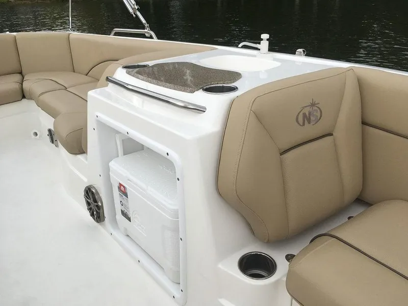 Slide: The Image of 2023 NauticStar 203SC Sport Deck interior with tan seating and built-in cooler. - 22