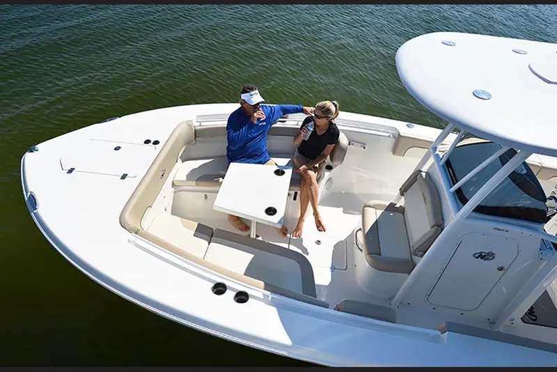 Slide: The Image of 2023 NauticStar 28 XS Offshore boat with two people relaxing on deck. - 18