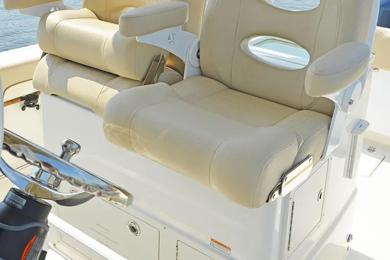 Slide: The Image of 2023 NauticStar 28 XS Offshore boat with beige captain's chairs and steering wheel. - 23