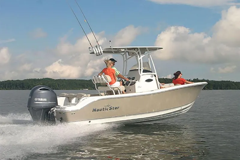Slide: The Image of 2023 NauticStar 2302 Legacy boat cruising on a lake with two passengers. - 13