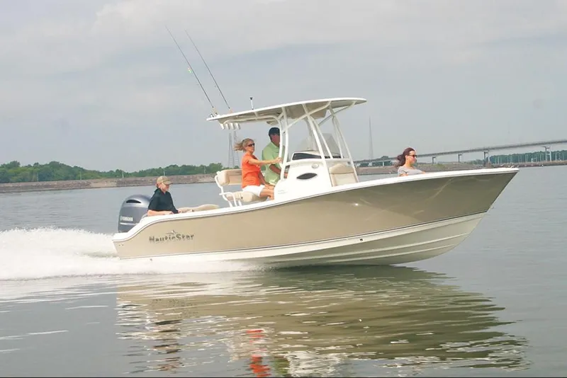 Slide: The Image of 2023 NauticStar 2302 Legacy boat cruising on a calm lake with passengers. - 14