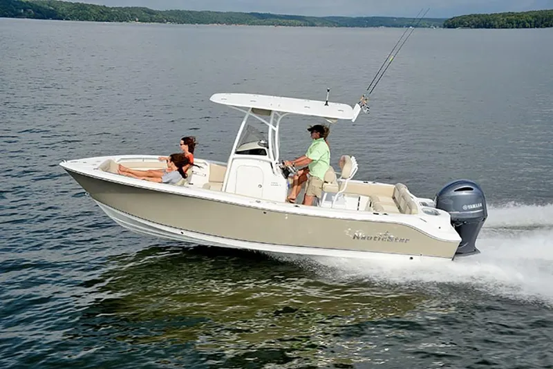 Slide: The Image of 2023 NauticStar 2302 Legacy boat cruising on a lake with two passengers. - 5
