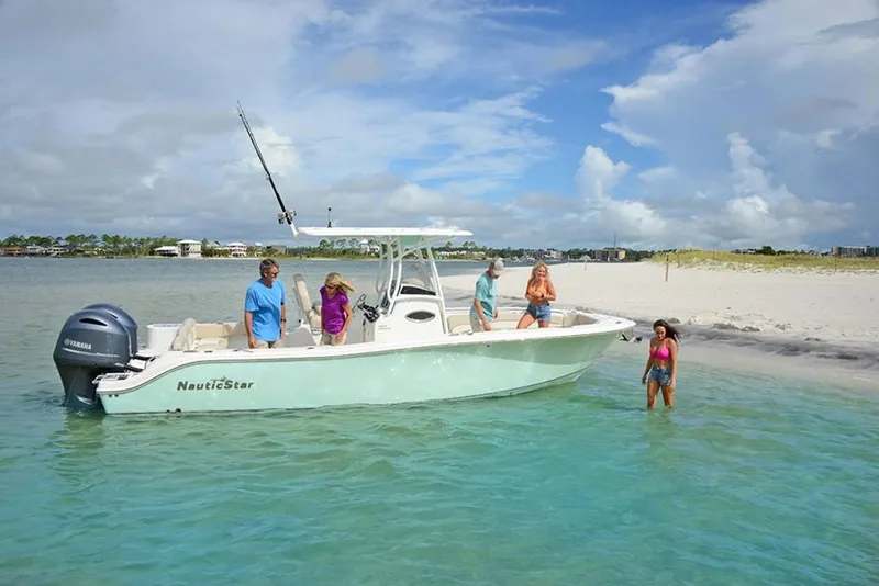Slide: The Image of 2023 NauticStar 2602 Legacy boat anchored near sandy beach with people enjoying the water. - 5