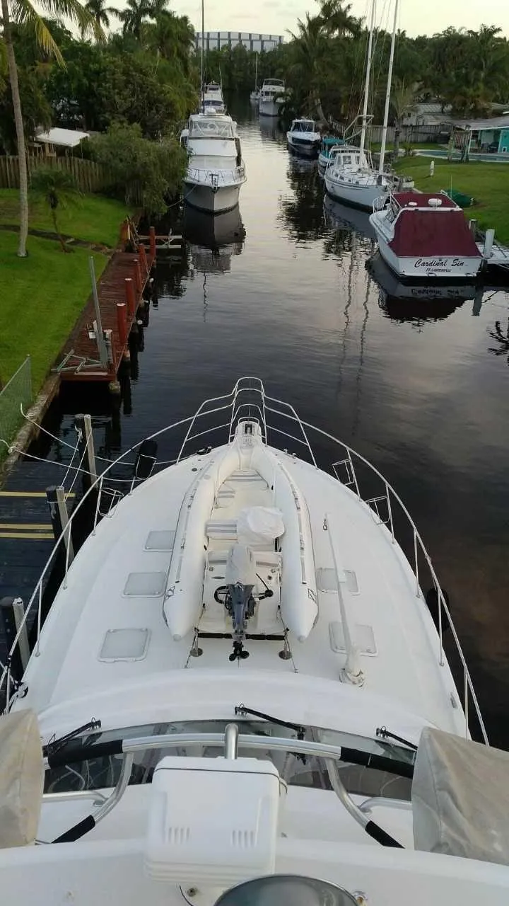 Slide: The Image of 2004 Riviera 58 Enclosed Flybridge yacht docked in a serene canal. - 13