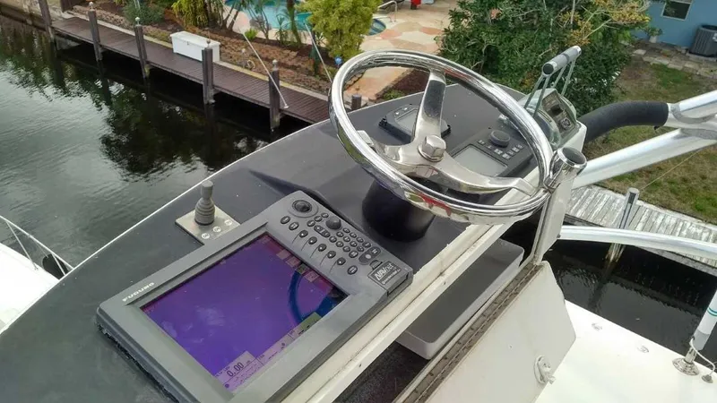 Slide: The Image of Control panel of a 2004 Riviera 58 Enclosed Flybridge yacht with steering wheel and navigation screen. - 16
