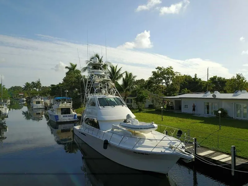 Slide: The Image of 2004 Riviera 58 Enclosed Flybridge yacht docked in a serene canal setting. - 2