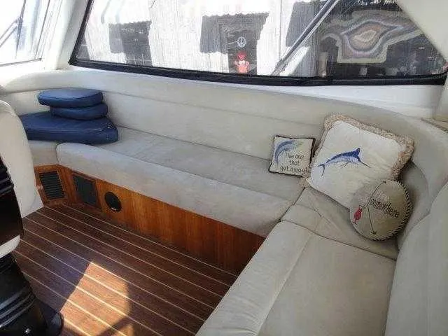 Slide: The Image of Interior seating area of 2004 Riviera 58 Enclosed Flybridge yacht with cushions and wooden flooring. - 42