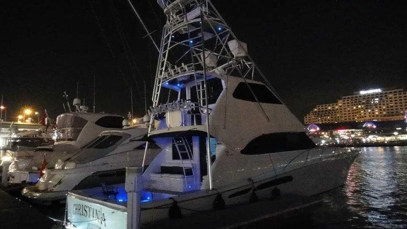 Slide: The Image of 2004 Riviera 58 Enclosed Flybridge yacht docked at night with illuminated blue lights. - 7