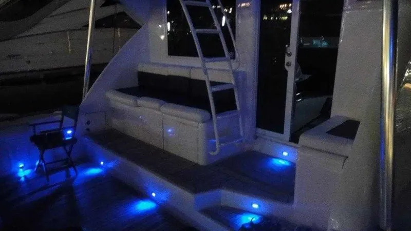 Slide: The Image of 2004 Riviera 58 Enclosed Flybridge yacht with blue LED deck lighting at night. - 9