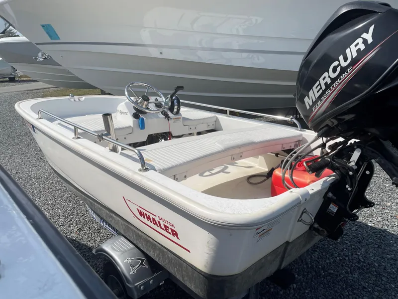 Slide: The Image of 2016 Boston Whaler 110 Sport boat with Mercury outboard motor, parked on gravel. - 1