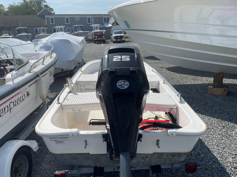 Slide: The Image of 2016 Boston Whaler 110 Sport boat with 25 HP engine, parked on gravel. - 3