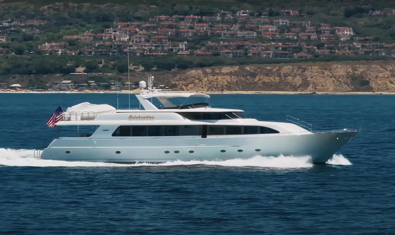 The Image of Luxurious 2000 Westport 112 yacht cruising near scenic coastline with hillside homes. - 0