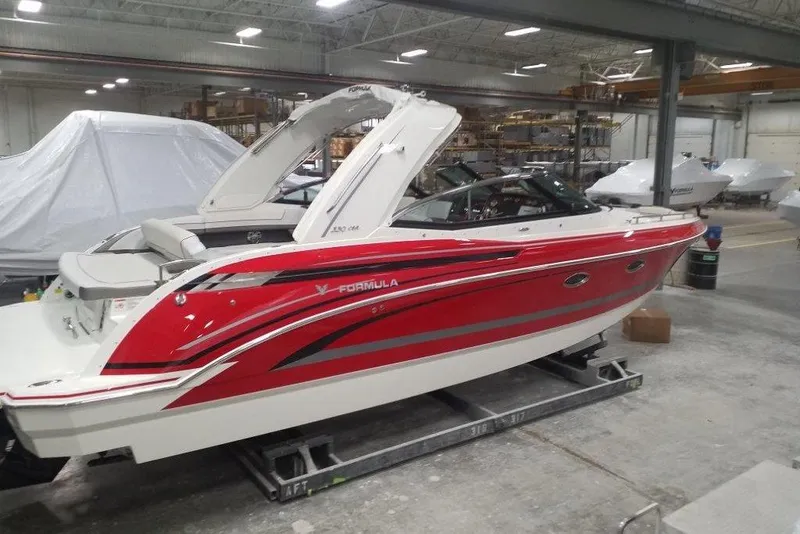 The Image of 2019 Formula 330 Crossover Bowrider in vibrant red, docked near a storage facility. - 0