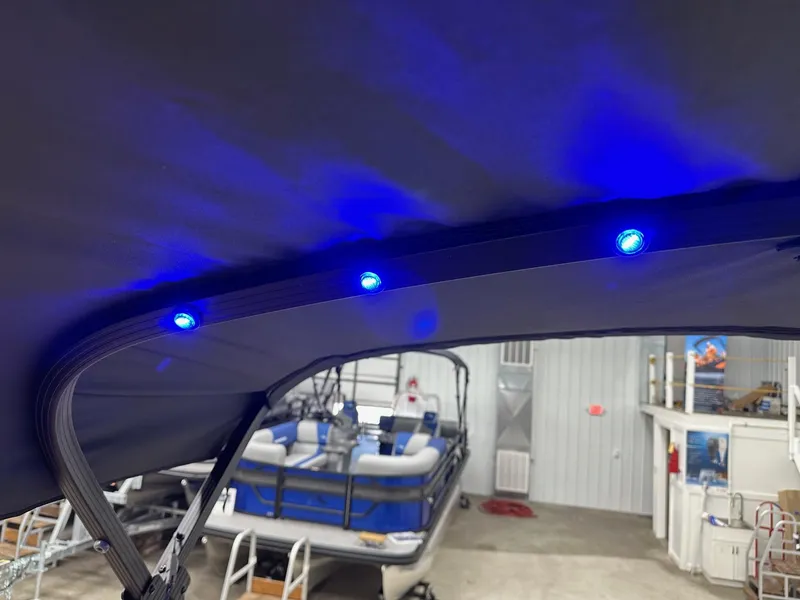 Slide: The Image of 2025 Bennington 21 SSR Quad Bench boat with blue LED canopy lights in showroom. - 14