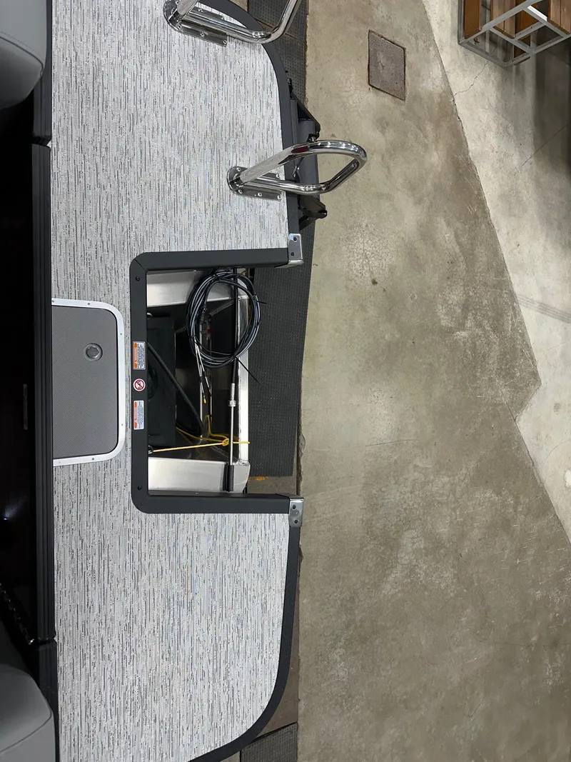 Slide: The Image of 2025 Bennington 21 SSR Quad Bench interior with open storage compartment and cables. - 15