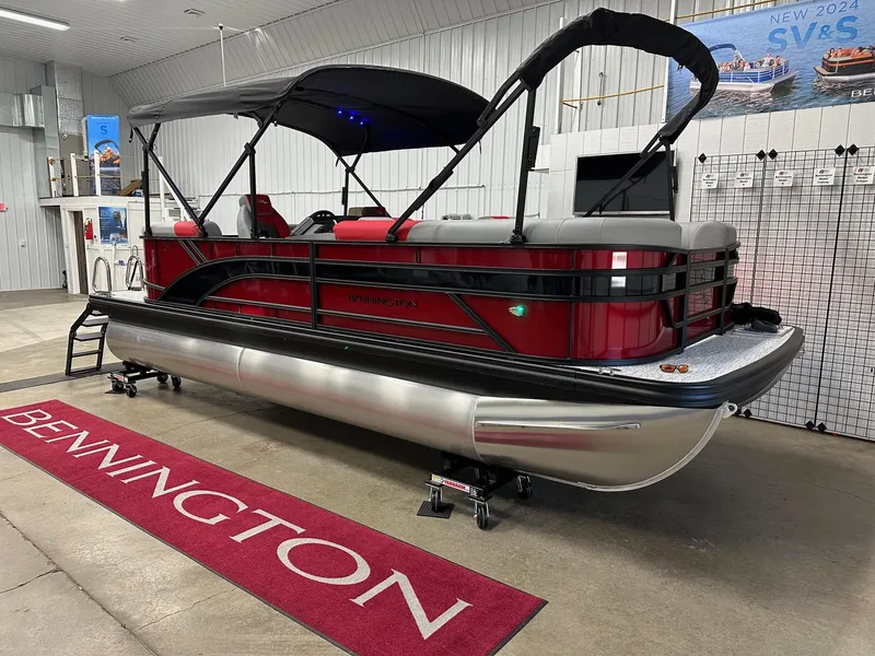 Slide: The Image of 2025 Bennington 21 SSR Quad Bench pontoon boat in showroom, red and silver design. - 19