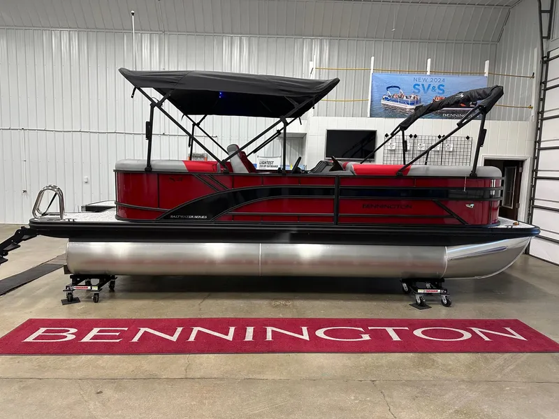 Slide: The Image of 2025 Bennington 21 SSR Quad Bench pontoon boat in showroom, red and black design. - 21