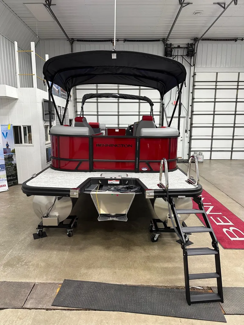 Slide: The Image of 2025 Bennington 21 SSR Quad Bench pontoon boat in showroom, rear view with ladder. - 22