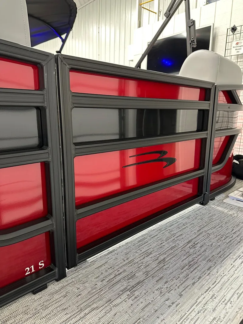 Slide: The Image of 2025 Bennington 21 SSR Quad Bench pontoon boat with sleek red paneling. - 23