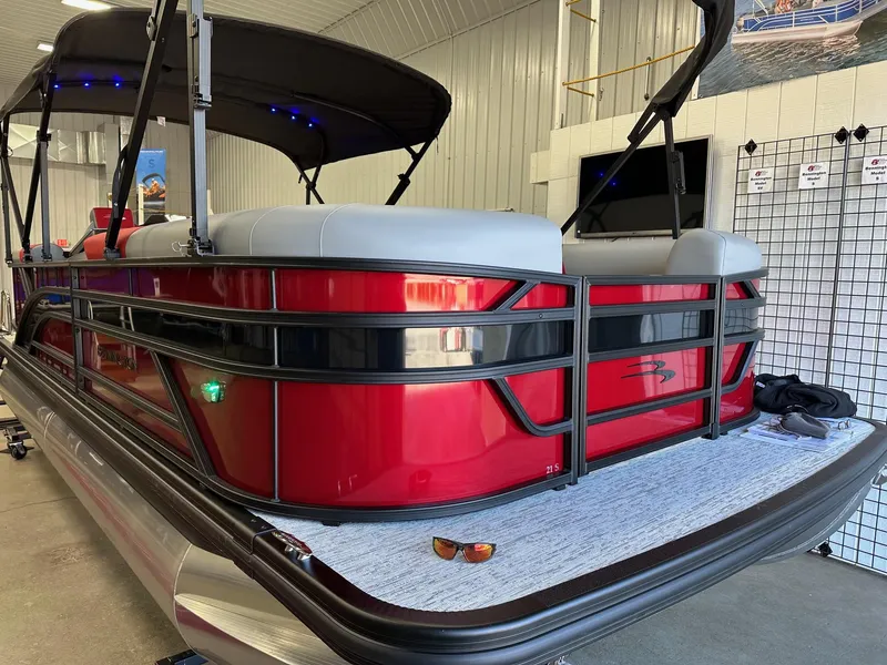 Slide: The Image of 2025 Bennington 21 SSR Quad Bench pontoon boat in stock, red exterior, indoor display. - 24