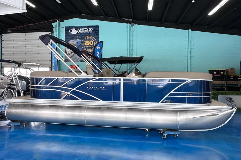 The Image of 2026 Sylvan Mirage 8522 LZ pontoon boat in showroom, blue and silver design. - 0