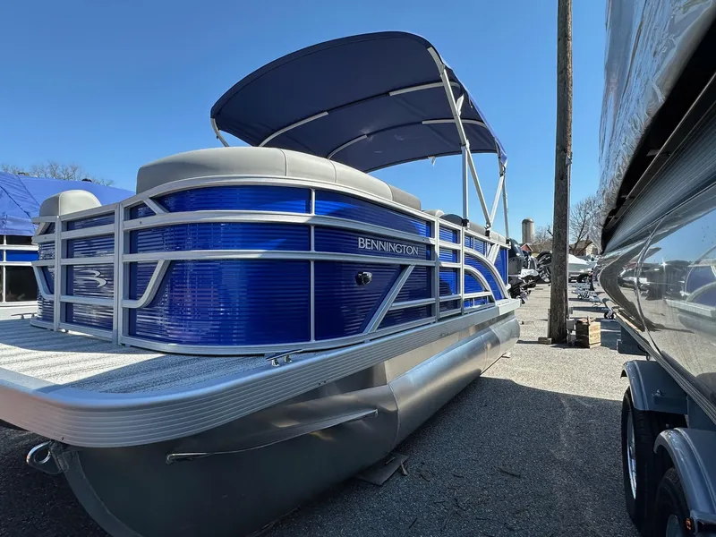 Slide: The Image of 2025 Bennington 168 SL pontoon boat with blue exterior and canopy, parked outdoors. - 12