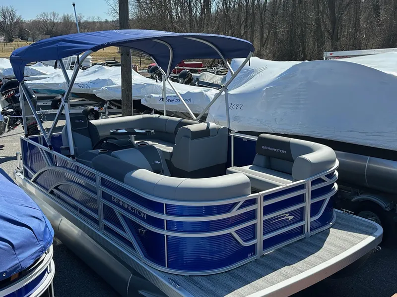Slide: The Image of 2025 Bennington 168 SL pontoon boat with blue canopy, in stock, parked outdoors. - 14