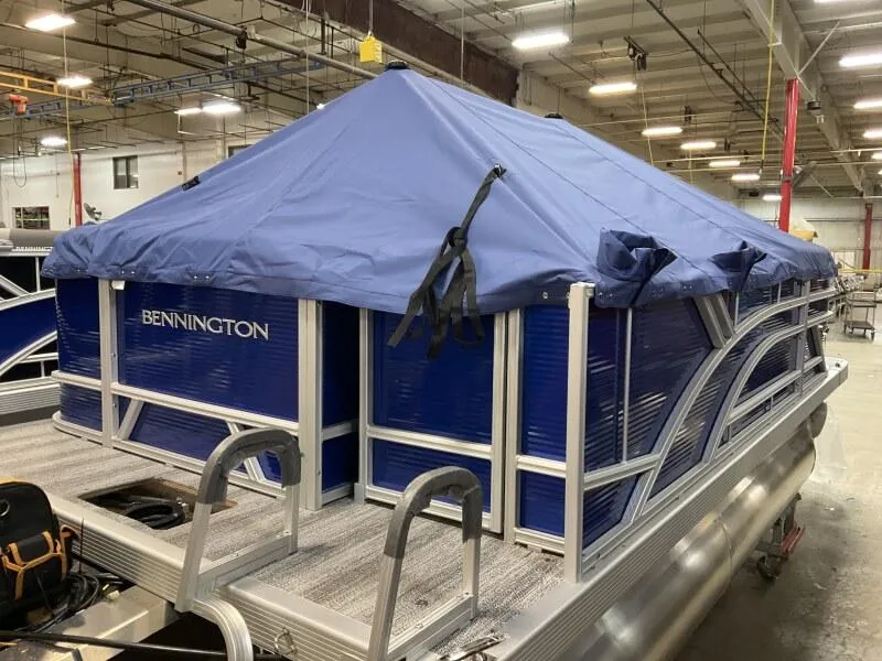 Slide: The Image of 2025 Bennington 168 SL pontoon boat with blue cover in warehouse setting. - 17