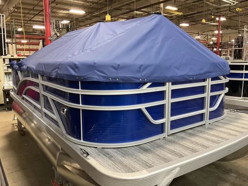 Slide: The Image of 2025 Bennington 168 SL pontoon boat with blue cover in warehouse setting. - 33